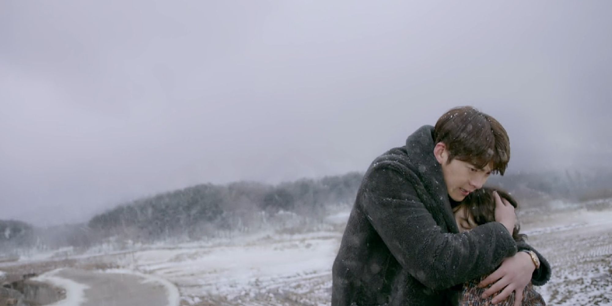 Two of the cast hold each other in a snowy landscape in Uncontrollably Fond.