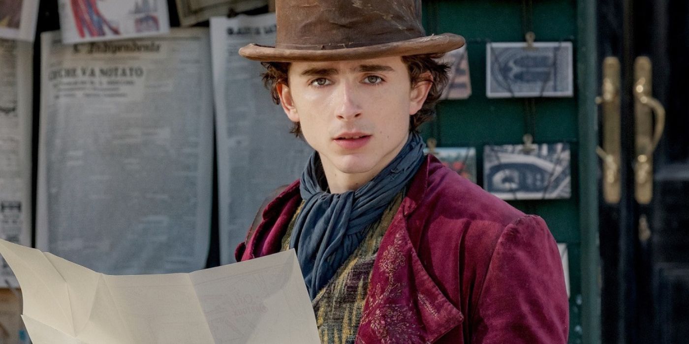 Timothee Chalamet as Willy Wonka holding a newspapaer and looking stunned in Wonka
