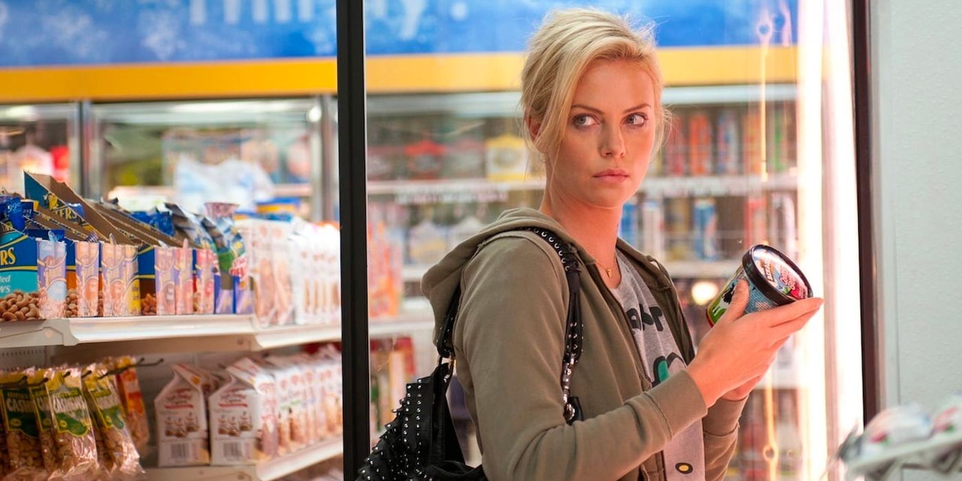 Charlize Theron as Mavis glares at someone while holding a tub of ice-cream in a store in Young Adult