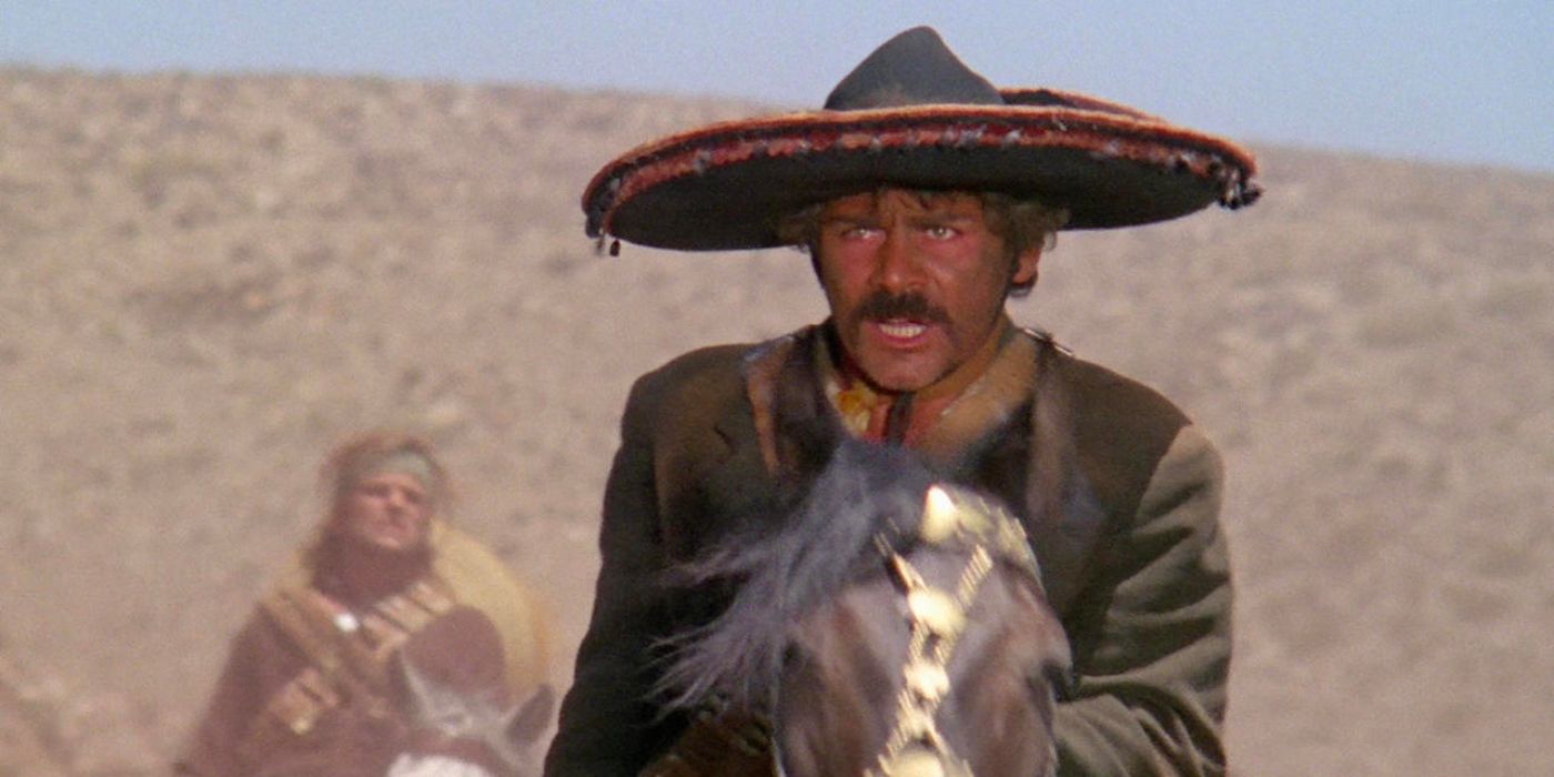 A Mexican revolutionary rides through the desert on horseback while his comrade rides follows behind him.