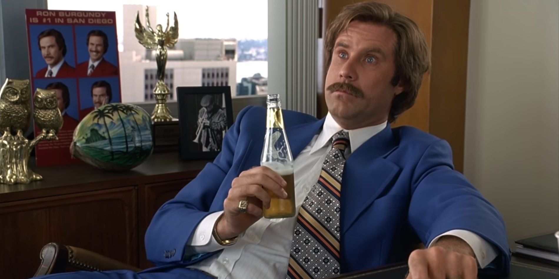 Ron Burgundy at his desk drinking some alcohol after the massive news station battle 