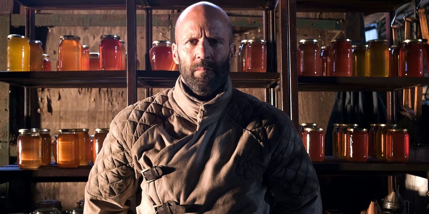 Jason Statham as Adam Clay, standing in front of jars of honey, in The Beekeeper