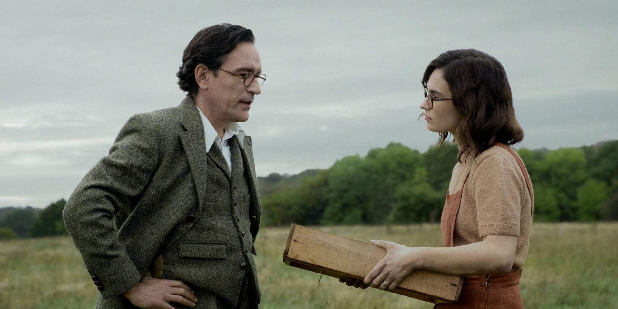 Ben Chaplin and Lily James as Stuart and Peggy Piggott, talking in a grass field in The Dig