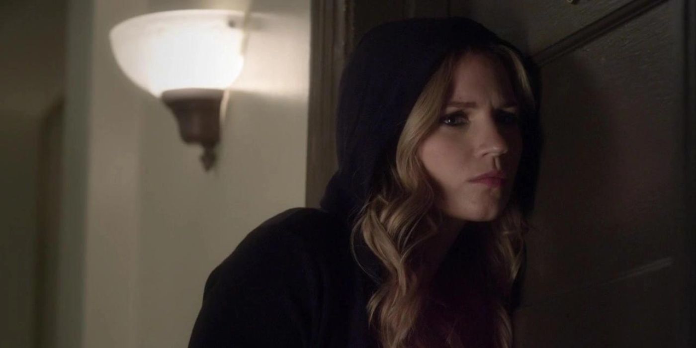 Cece (Vanessa Ray) wearing a black hood, listening against a door in Pretty Little Liars