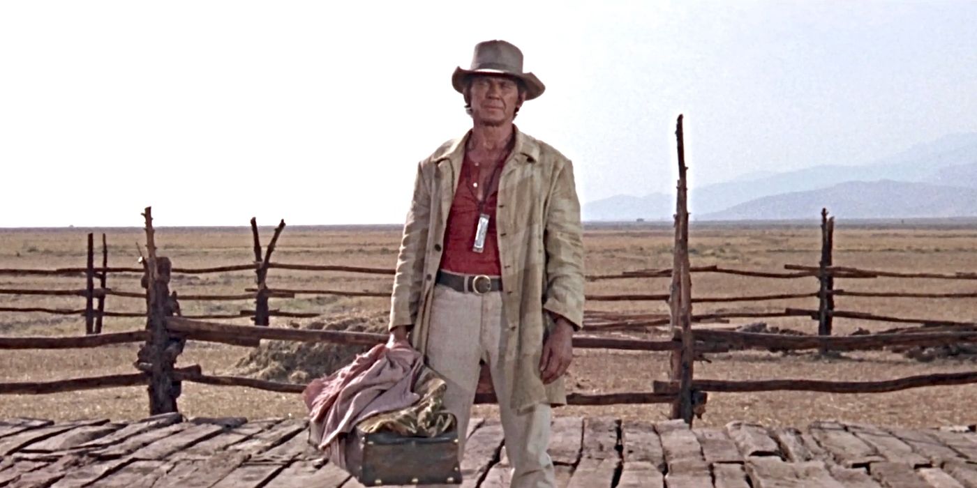 Charles Bronson as Harmonica, wearing his harmonica and standing with luggage in Once Upon a Time in the West