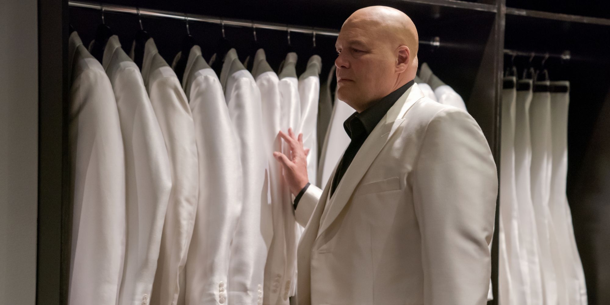 Wilson Fisk (Vincent D'Onofrio) in front of a closet of white suits, touching several in Daredevil