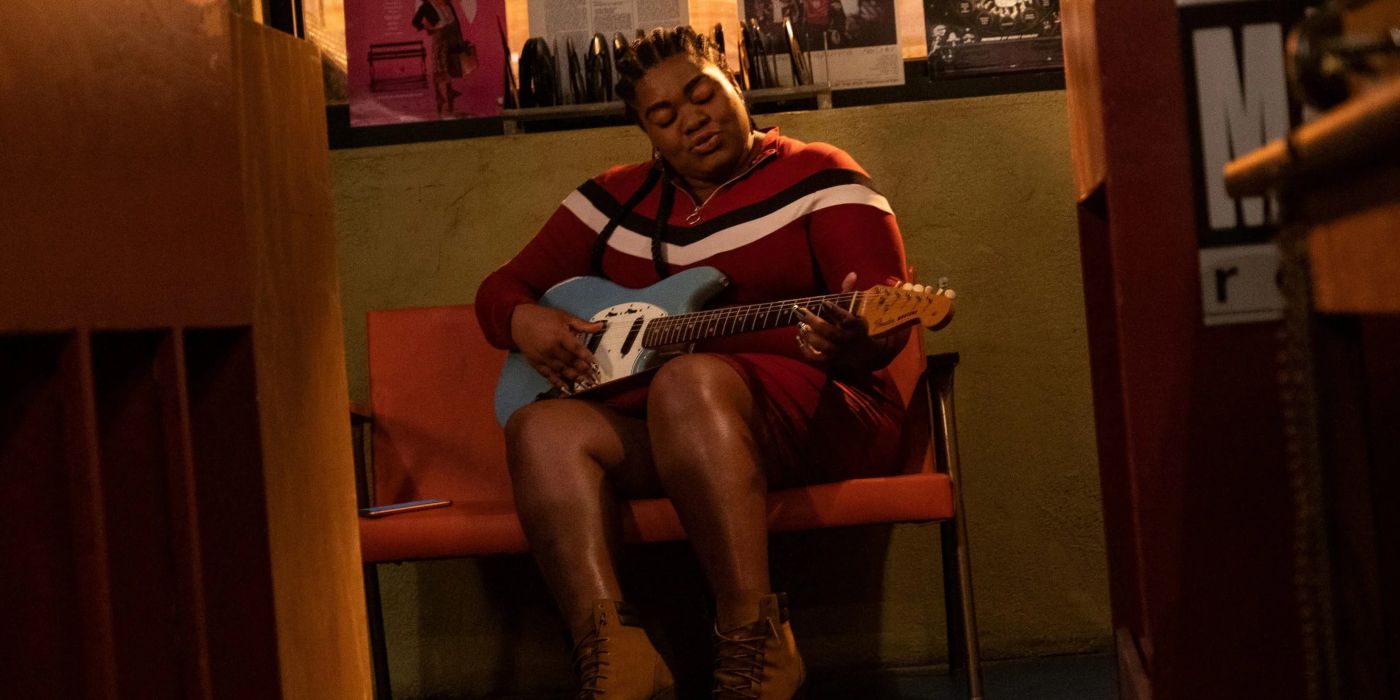 Da'Vine Joy Randolph's Cherise sits in a chair and plays guitar in Hulu's High Fidelity