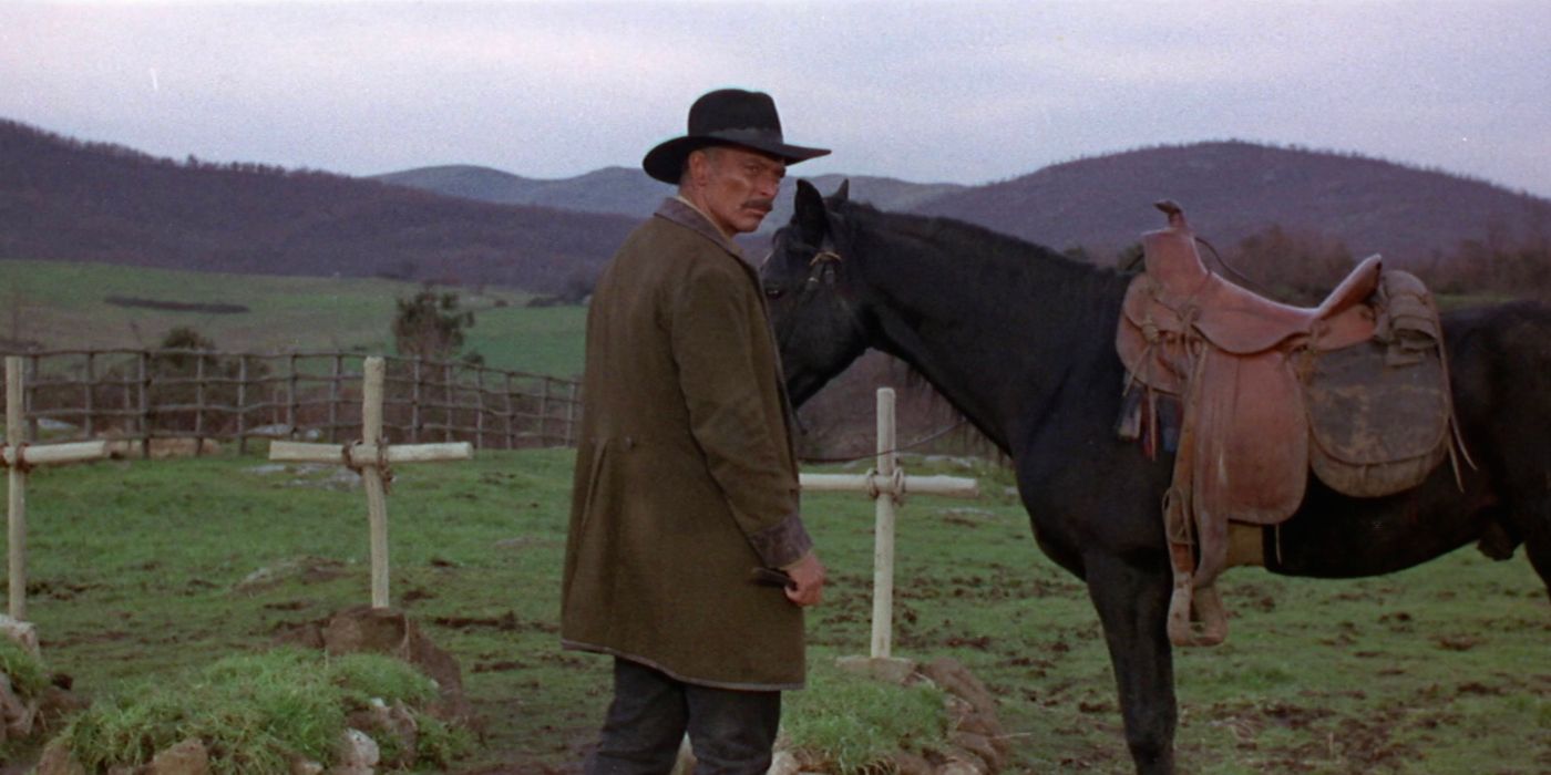 Lee Van Cleef tends to his horse while peering over his shoulder in a fresh graveyard in Death Rides a Horse