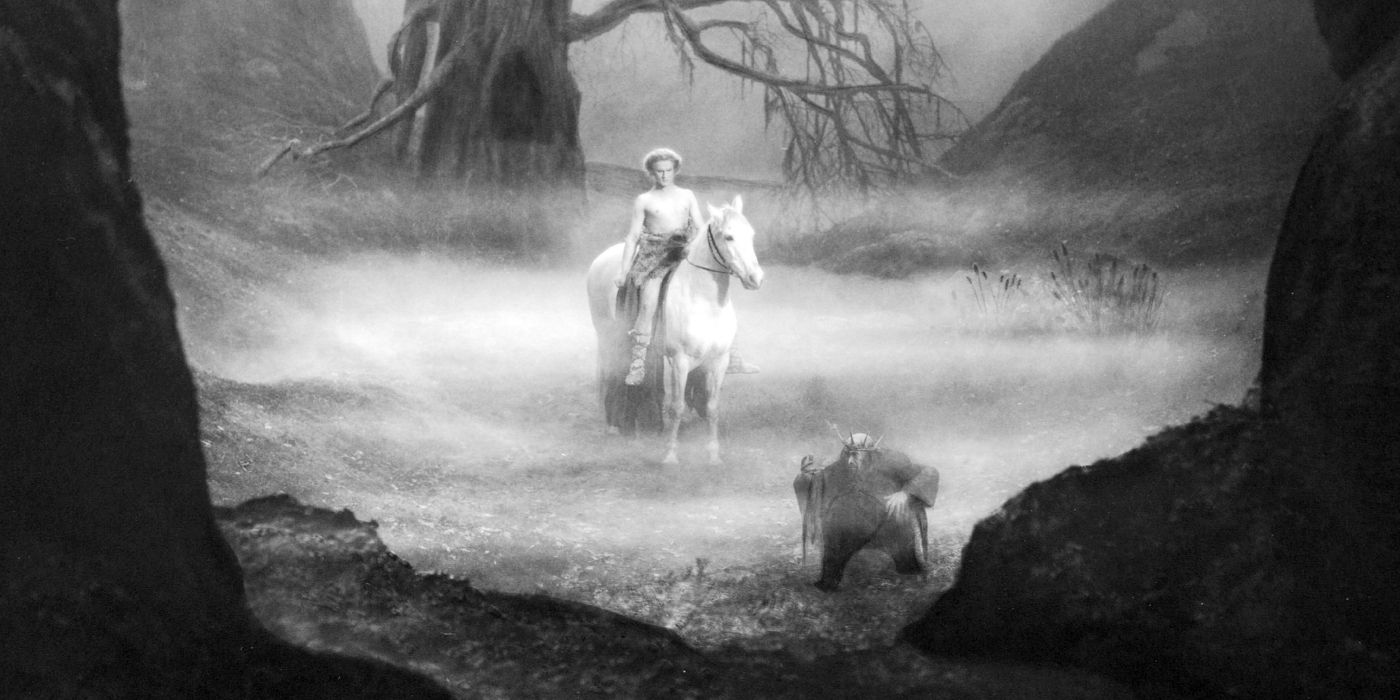 A warrior on horseback approaches a dwarf king through a misty gulch in the woods.