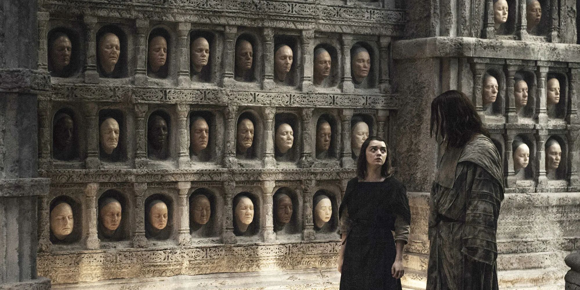 Jaqen H'ghar (Tom Wlaschiha) and Arya Stark (Maisie Williams) walking past faces in 'Game of Thrones'