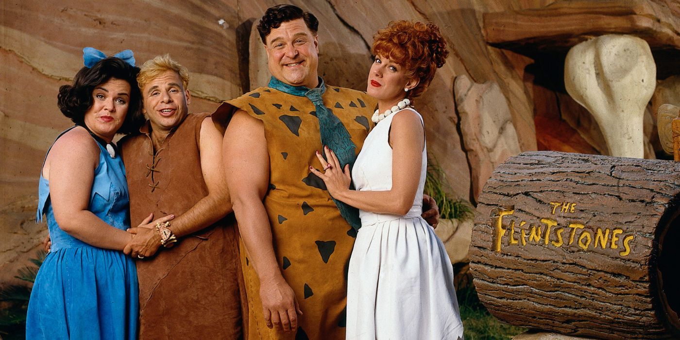 Rosie O&rsquo;Donnell, Rick Moranis, John Goodman, and Elizabeth Perkins as Betty Rubble, Barney Rubble, Fred Flintstone, and Wilma Flinstone in the live-action Flintstones movie