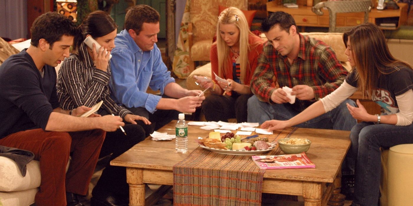 The six main cast members sitting down around a coffee table in Friends