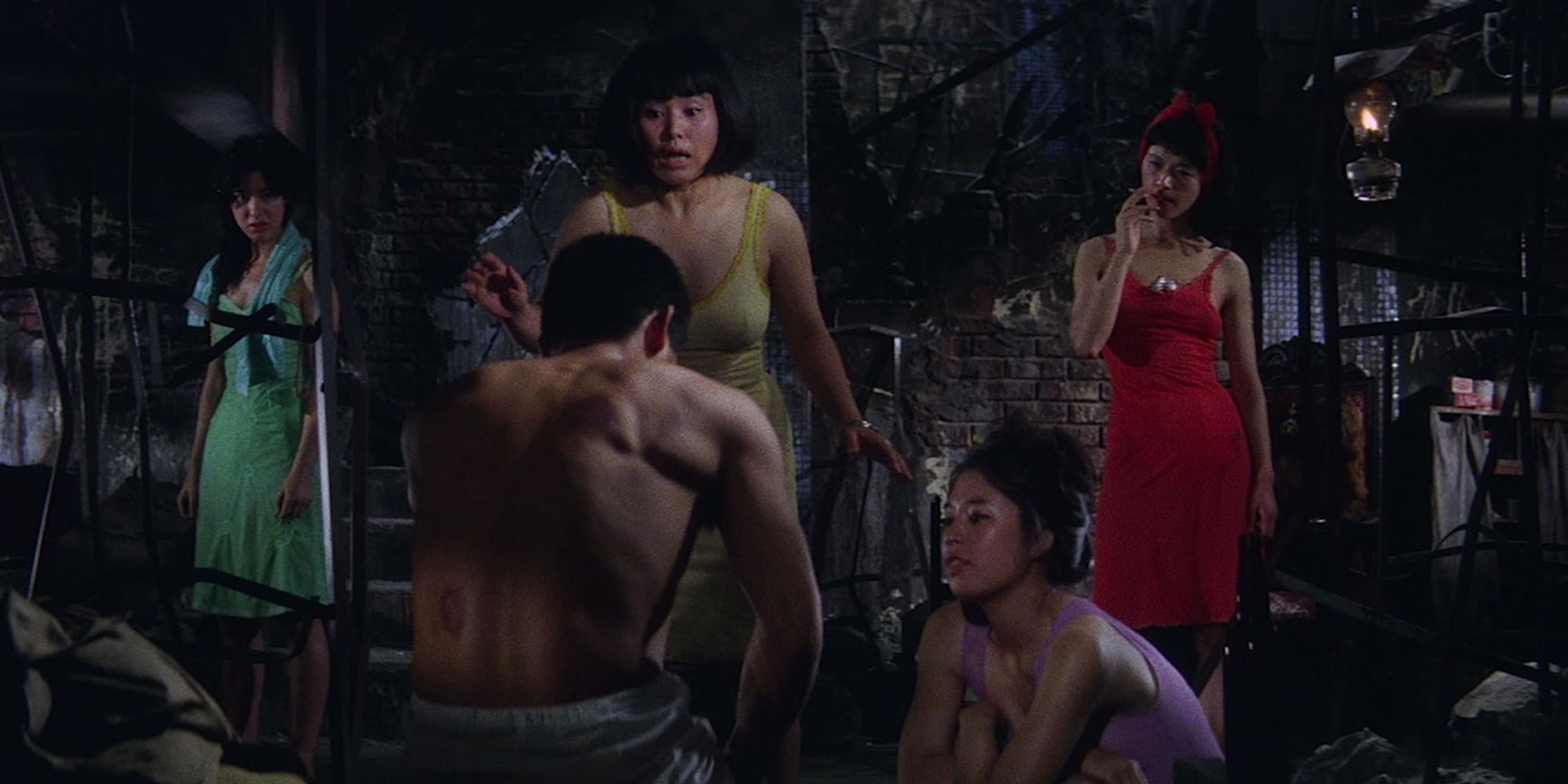 A shirtless man and women in dresses in Gate of Flesh 1964