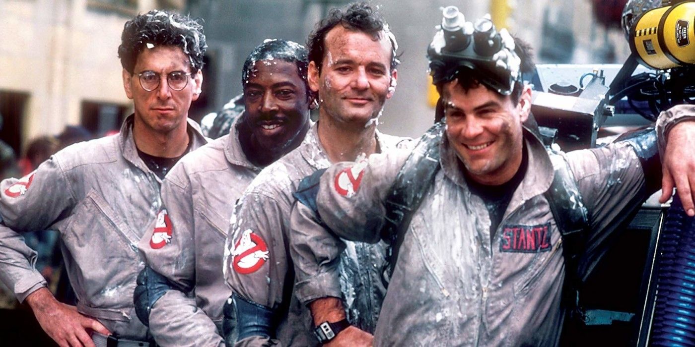 The Ghostbusters team, dirty and covered in marshmallow, poses by the Ecto-1 in 'Ghostbusters'