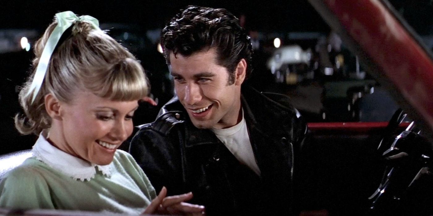 Sandy (left) sits in a car with Danny (right) in Grease.