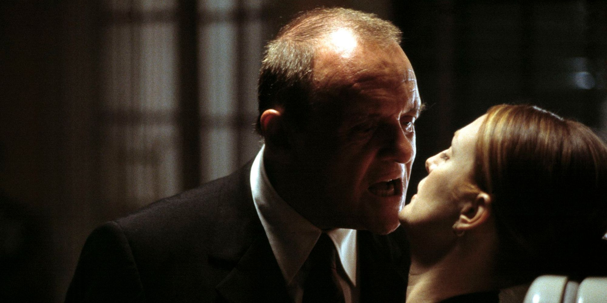 Hannibal Lecter, played by Anthony Hopkins, leaning in close to Julianne Moore's Clarice Starling with his mouth open about to bite her lips or kiss her, in Hannibal the movie