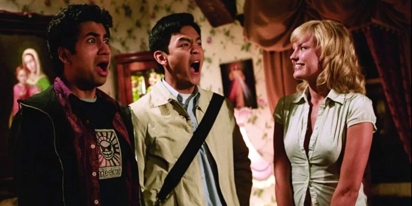 Two young men stand in a room screaming in shock while a blonde woman smiles at them.
