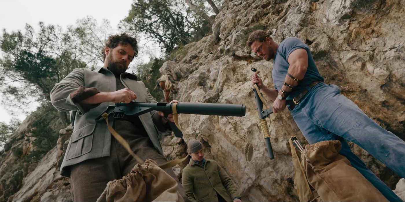 Henry Cavill, Alan Ritchson, and Hero Fiennes Tiffin, loading their weapons underneath a cliff