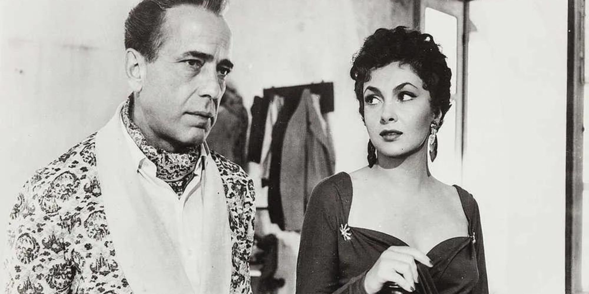 Humphrey Bogart standing next to Gina Lollobrigida in Beat the Devil (1953)