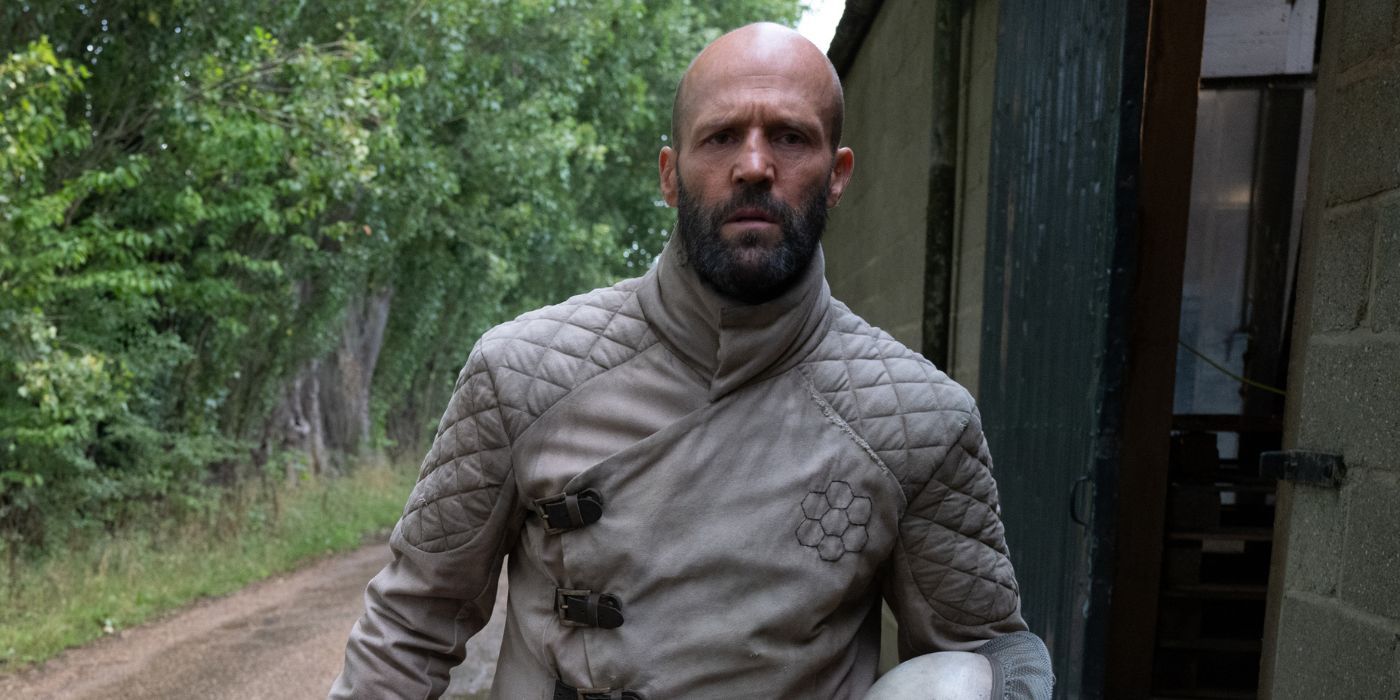 Jason Statham as Adam Clay with an intent look on his face walks outside in The Beekeeper