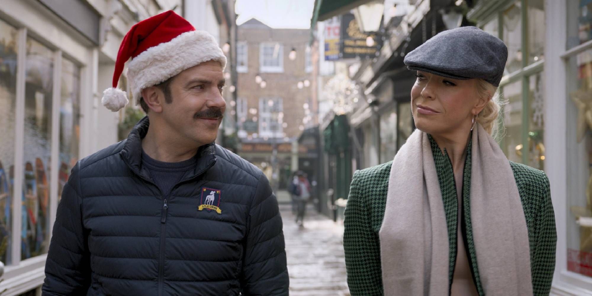 Jason Sudeikis and Hannah Waddingham looking at each other and smiling with Christmas hats on in Ted Lasso