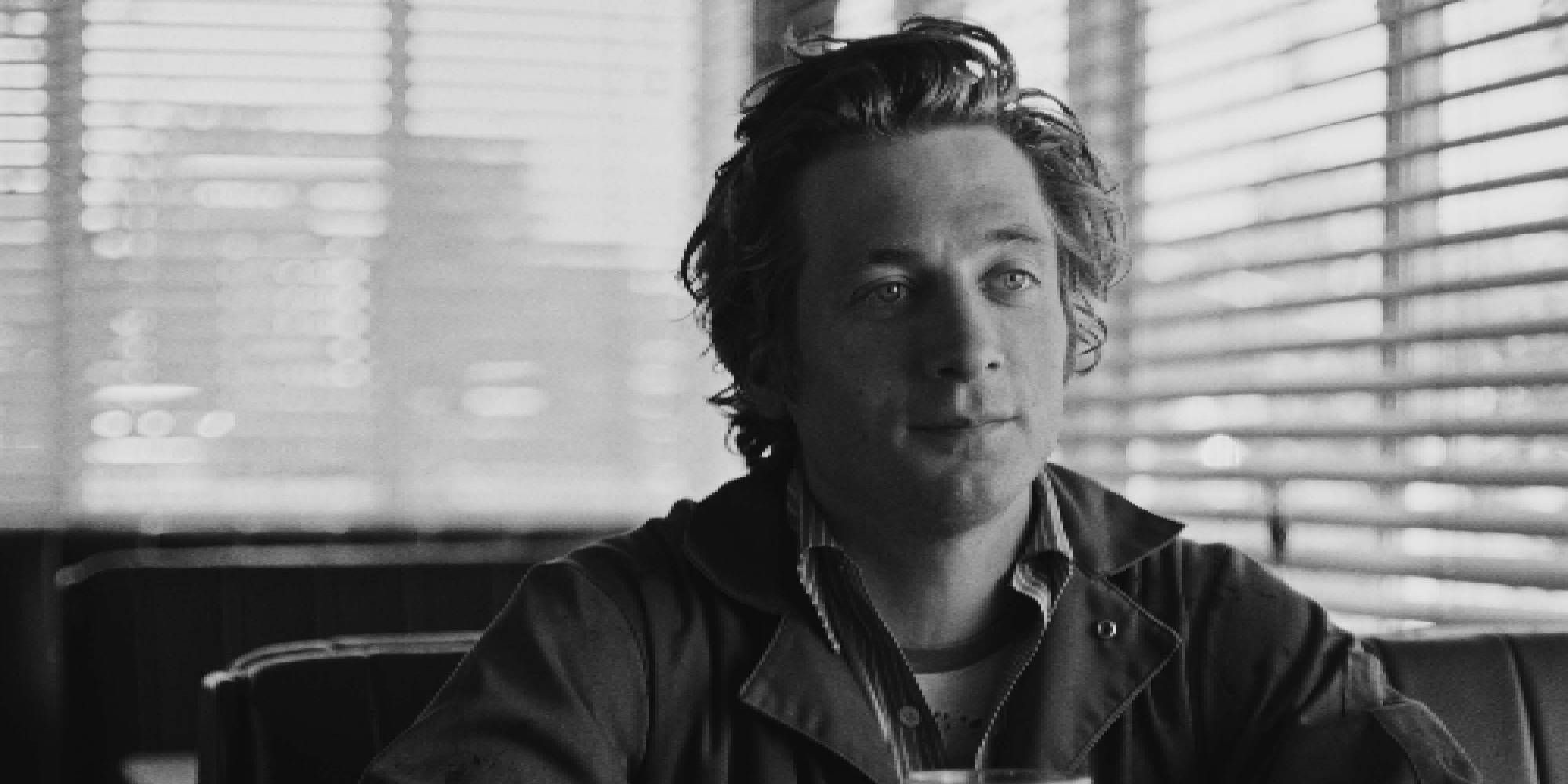 Black and white shot of Jeremy Allen White smiling while sitting at a café in Fremont