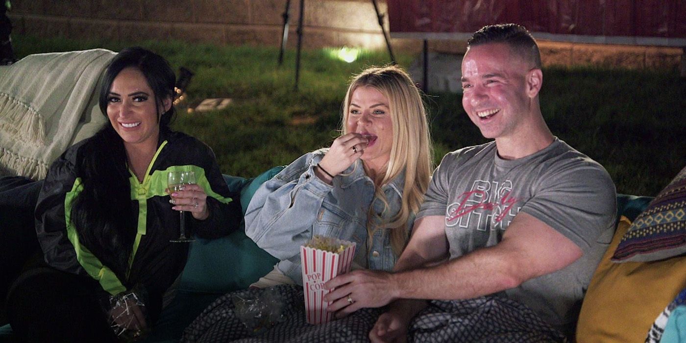 Mike, Lauren, and Angelina smiling, eating popcorn outside in a scene from Jersey Shore: Family Vacation.