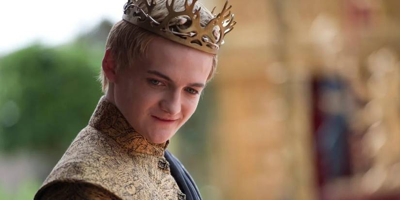 Jack Gleeson as Joffrey Baratheon with a crown and smug smile in Game of Thrones