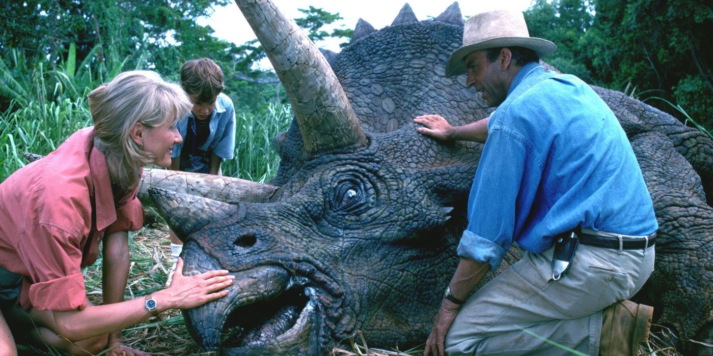 Ellie, Tim, and Alan kneeling down and petting a sick triceratops in Jurassic Park