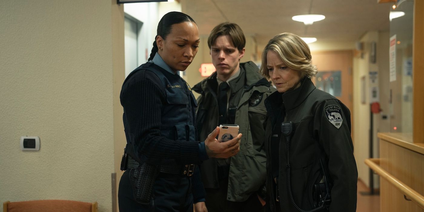 Kali Reis, Finn Bennett, and Jodie Foster gather around at a phone in True Detective: Night Country