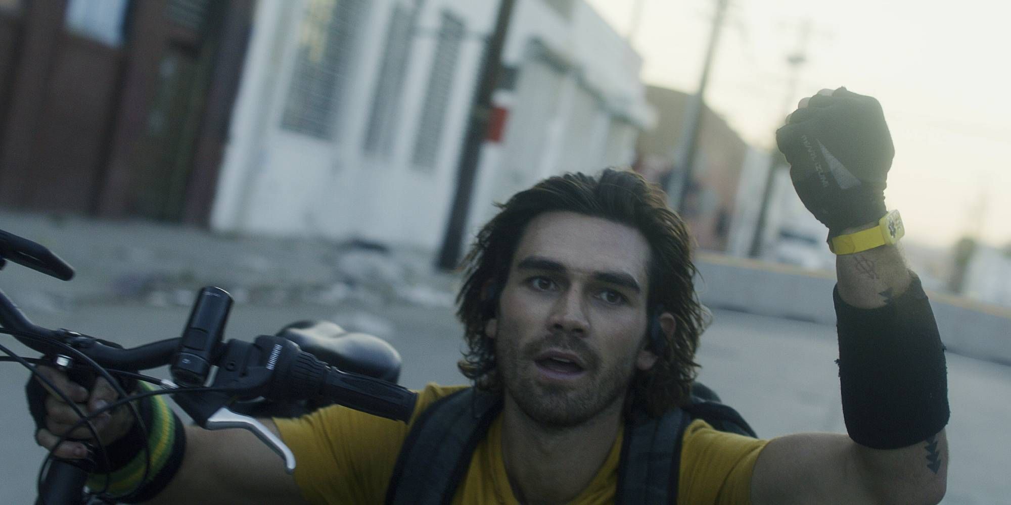 KJ Apa holding onto a bike in Songbird