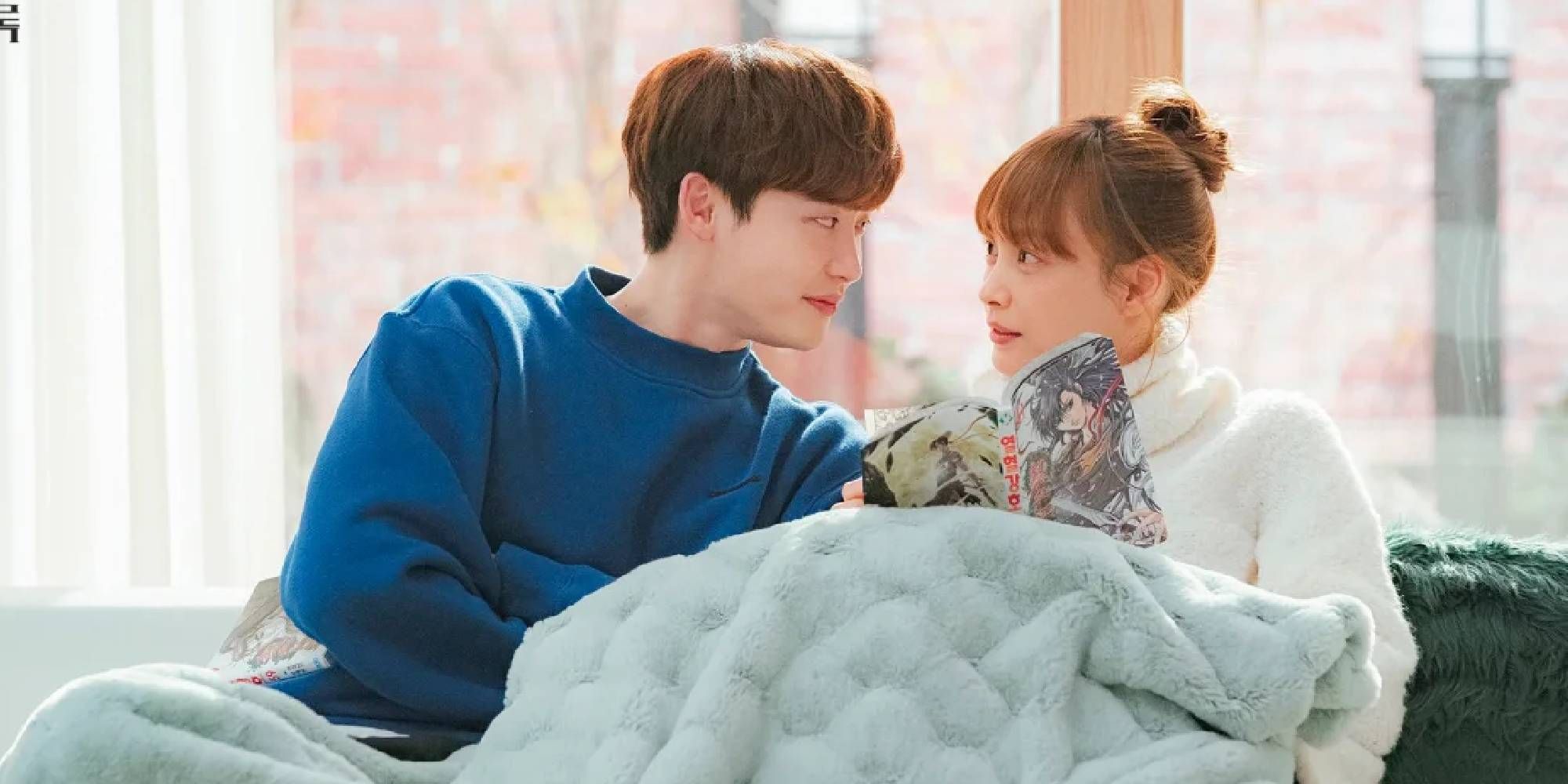 Lee Na-young &amp; Lee Jong-suk cuddling and looking at each other sitting on the sofa in Romance is a Bonus Book.