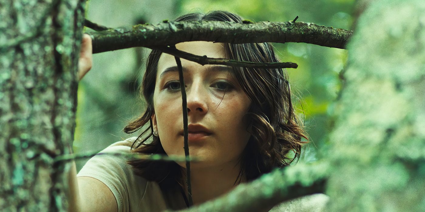 Lilly Collias as Sam looks through branches while on a hike with her dad and his friend in Good One. 