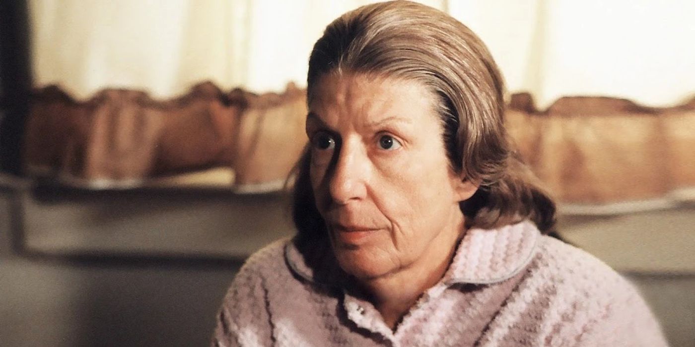 Livia Soprano sits in front of a window with curtains and looks serious in The Sopranos.