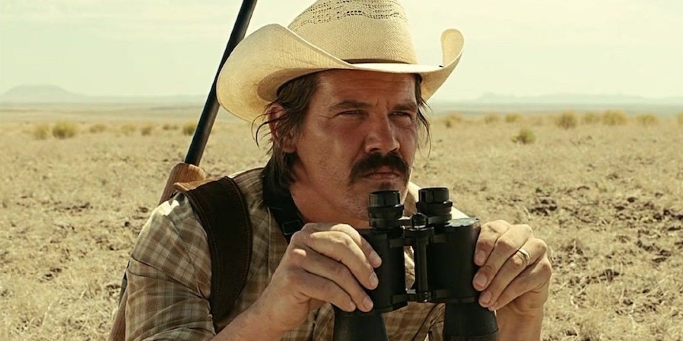 Llewelyn Moss (Josh Brolin) holding binoculars in a desert 'No Country for Old Men'