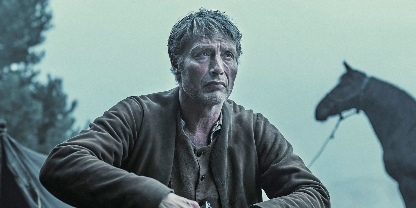 Mads Mikkelsen as Ludvig Kahlen sitting in front of a tent and horse in the remote Jutland Heath in Denmark in The Promised Land. 