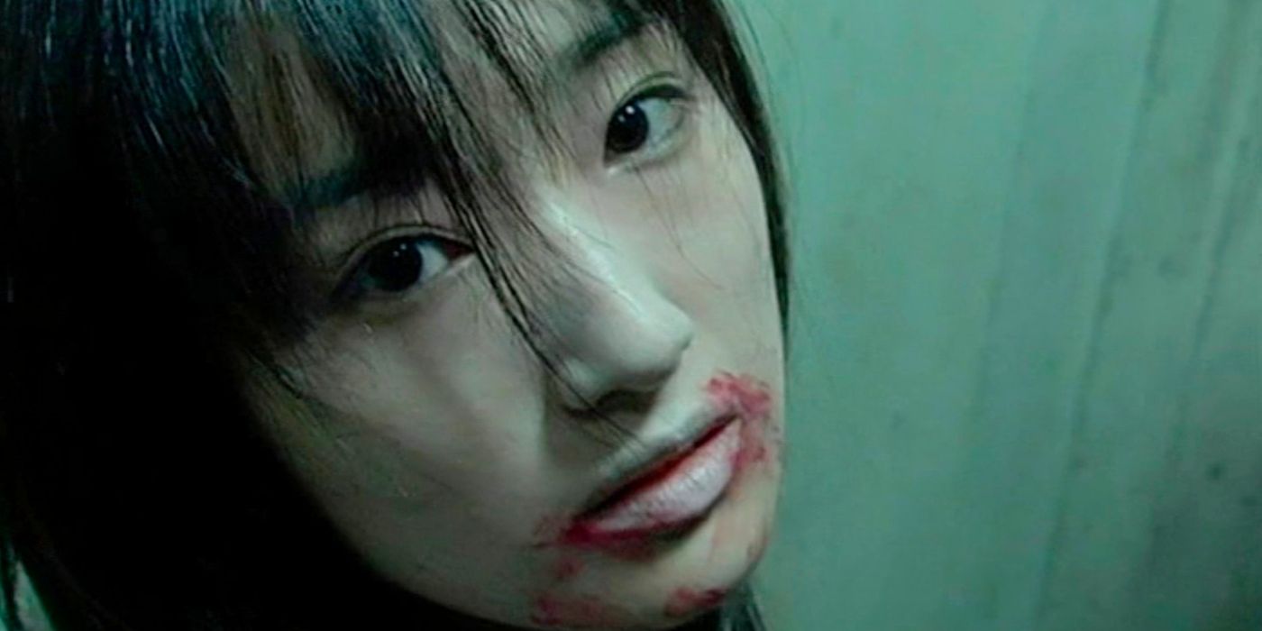 A woman with a bloodied mouth looks down the barrel of the camera.