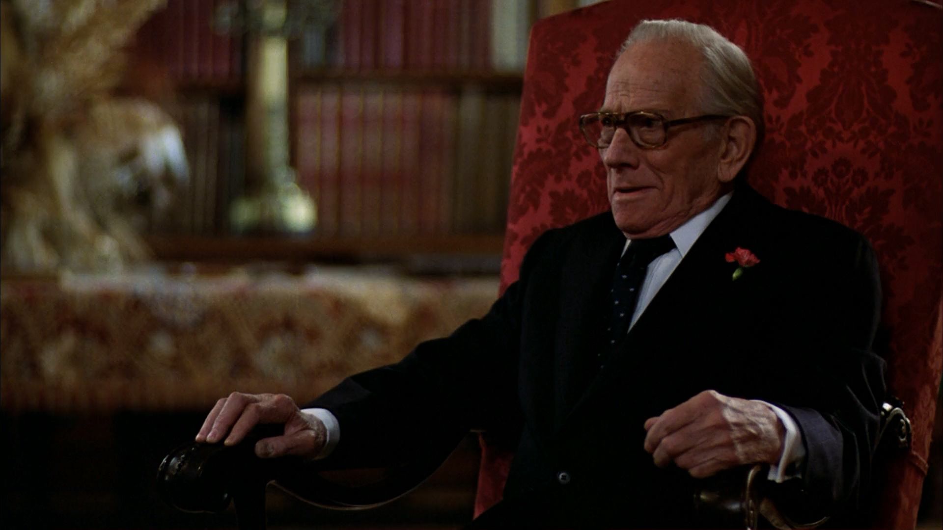 Melvyn Douglas as an old man in suit, sitting on a big red chair