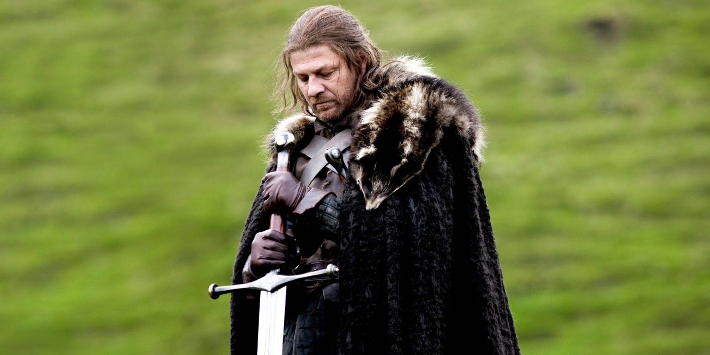 Ned Stark standing in a green field and holding a sword in Game of Thrones