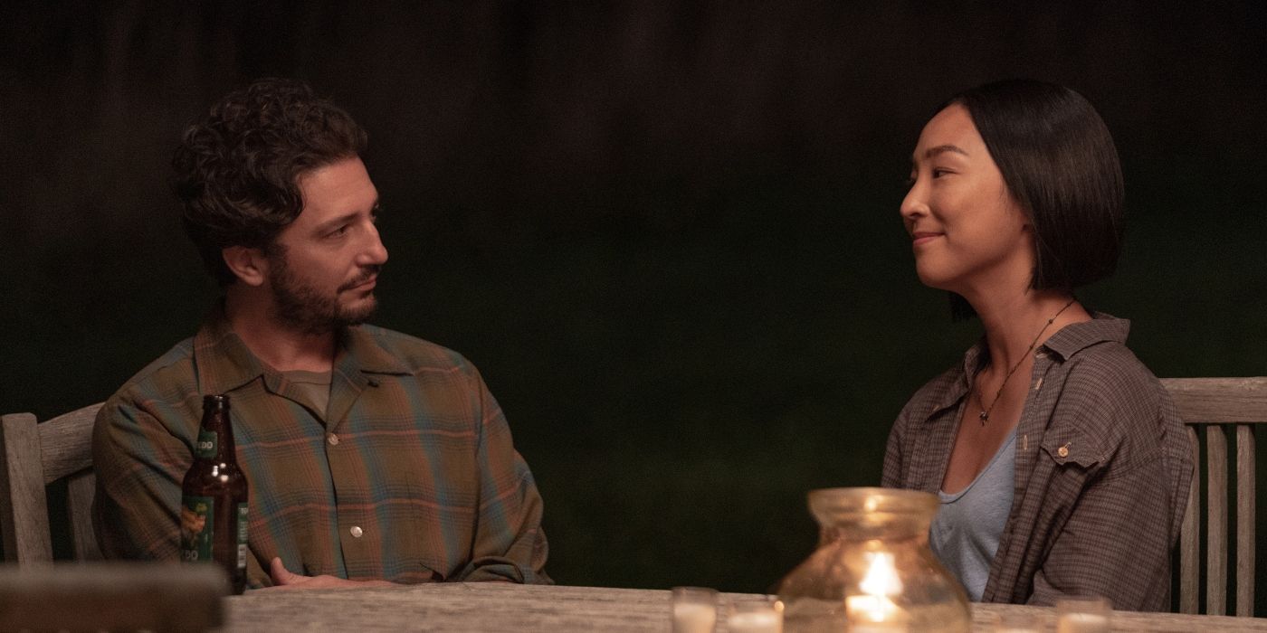 Greta Lee and John Magaro talk and smile at a table in Past Lives