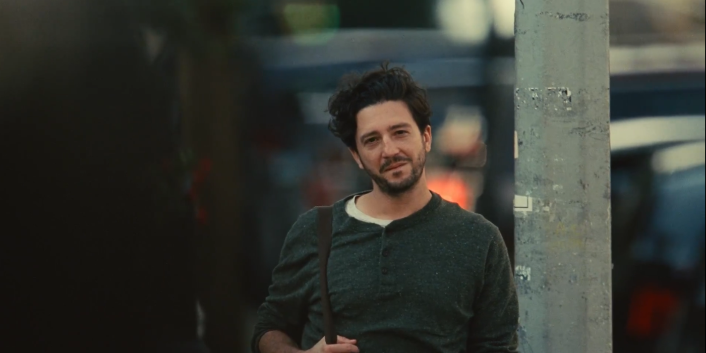 Arthur, played by John Magaro, stands at a crossing in the movie Past Lives