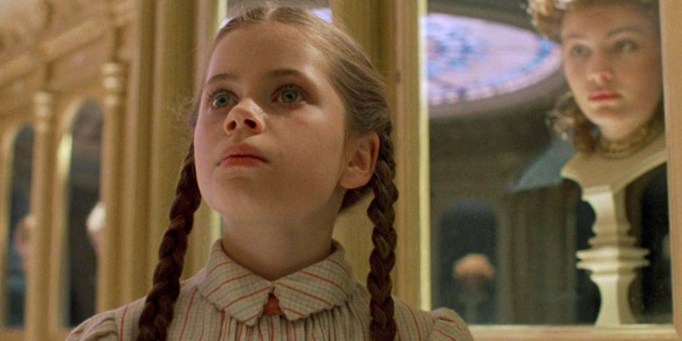 Dorothy standing in the hall of faces with a decapitated head in a display case behind her