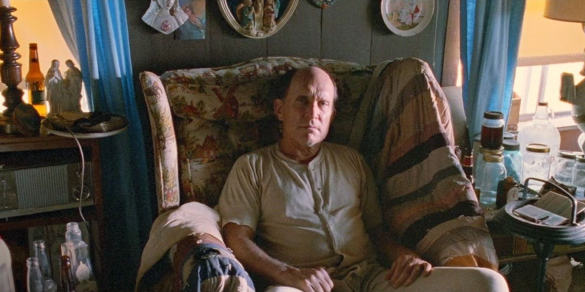 Robert Duvall as Frank Childers, sitting in an armchair and looking towards the camera in Sling Blade