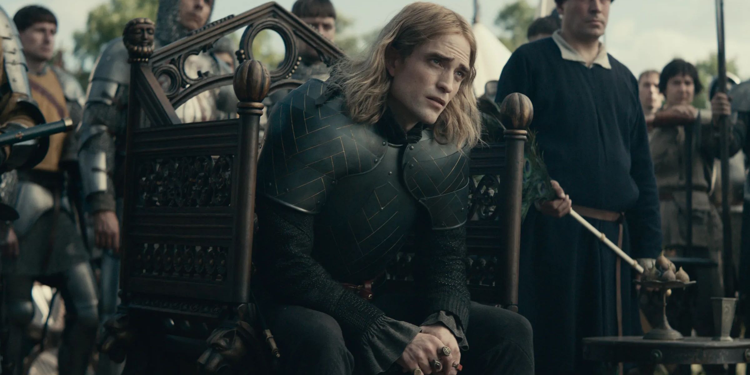 The Dauphen (Robert Pattinson) sitting in a small throne in The King