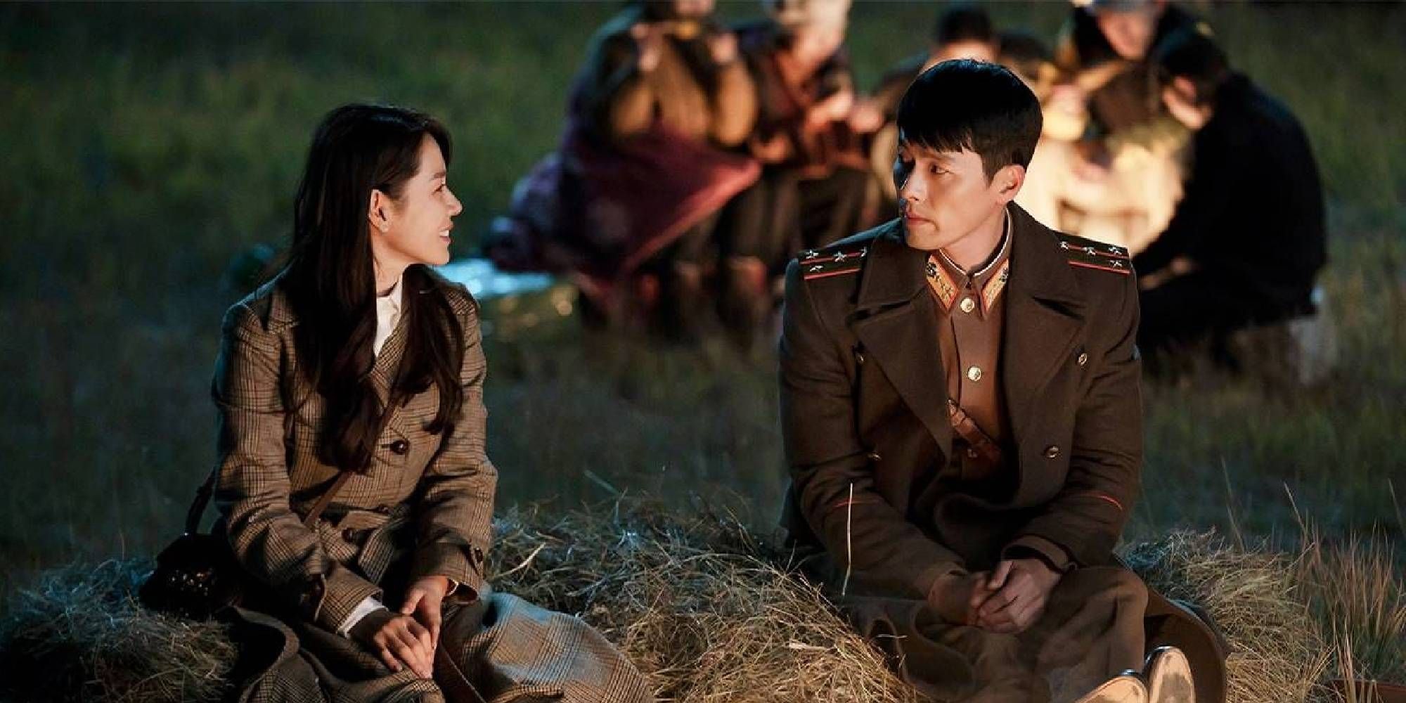 Se Ri and Jeong Hyeok sit by a fire outside in Crash Landing on You.