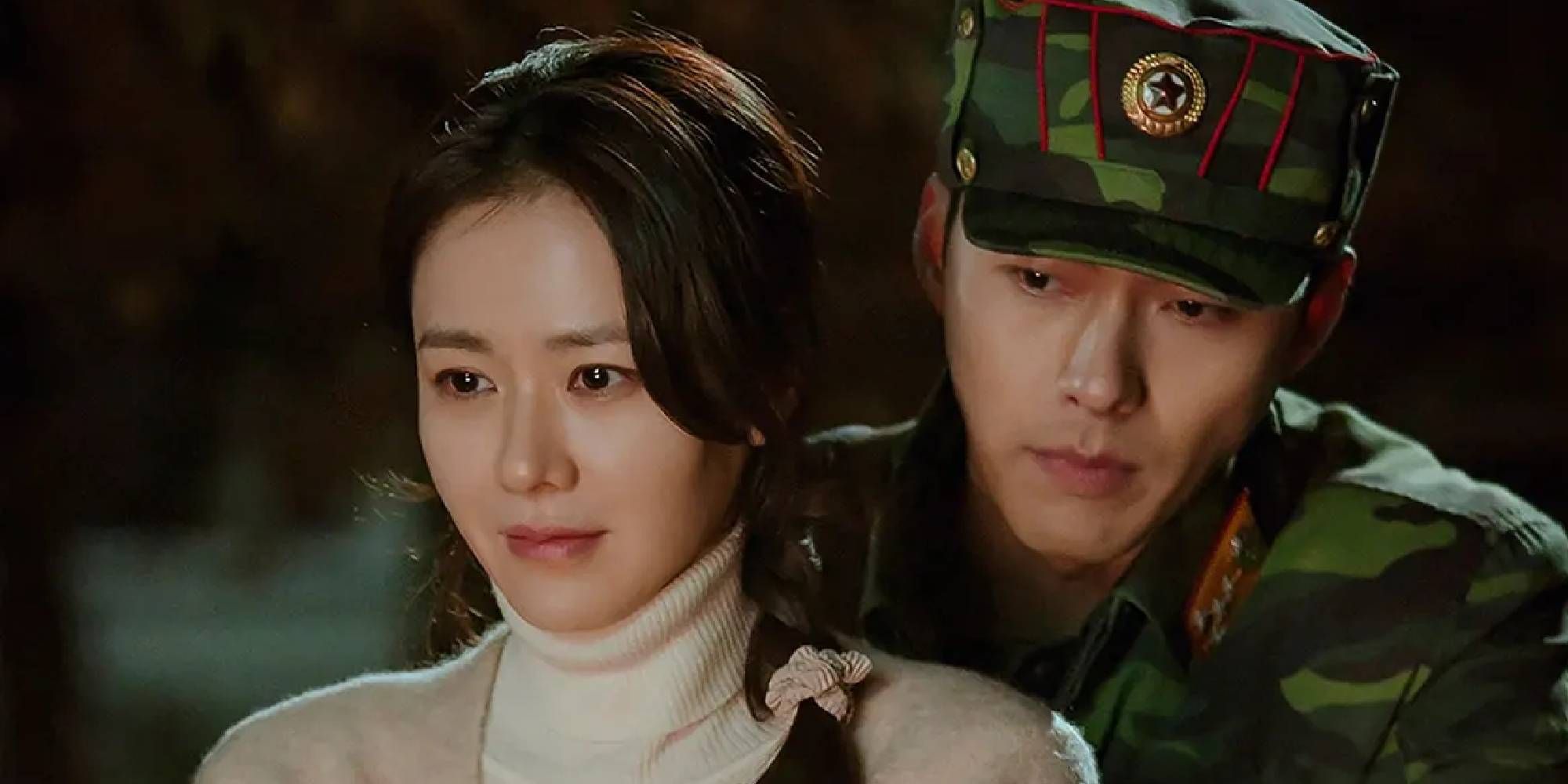 Jeong Hyeok (Hyun Bin) in uniform stands close behind Se Ri (Son Ye-jin) in Crash Landing on You. 