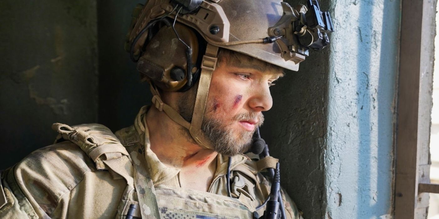 Max Thieriot as Clay Spenser in military gear, looking sadly out a window in SEAL Team