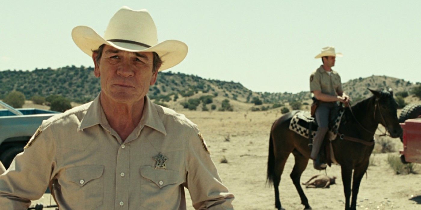 Sheriff Bell (Tommy Lee Jones) standing in a desert near an officer in 'No Country for Old Men'