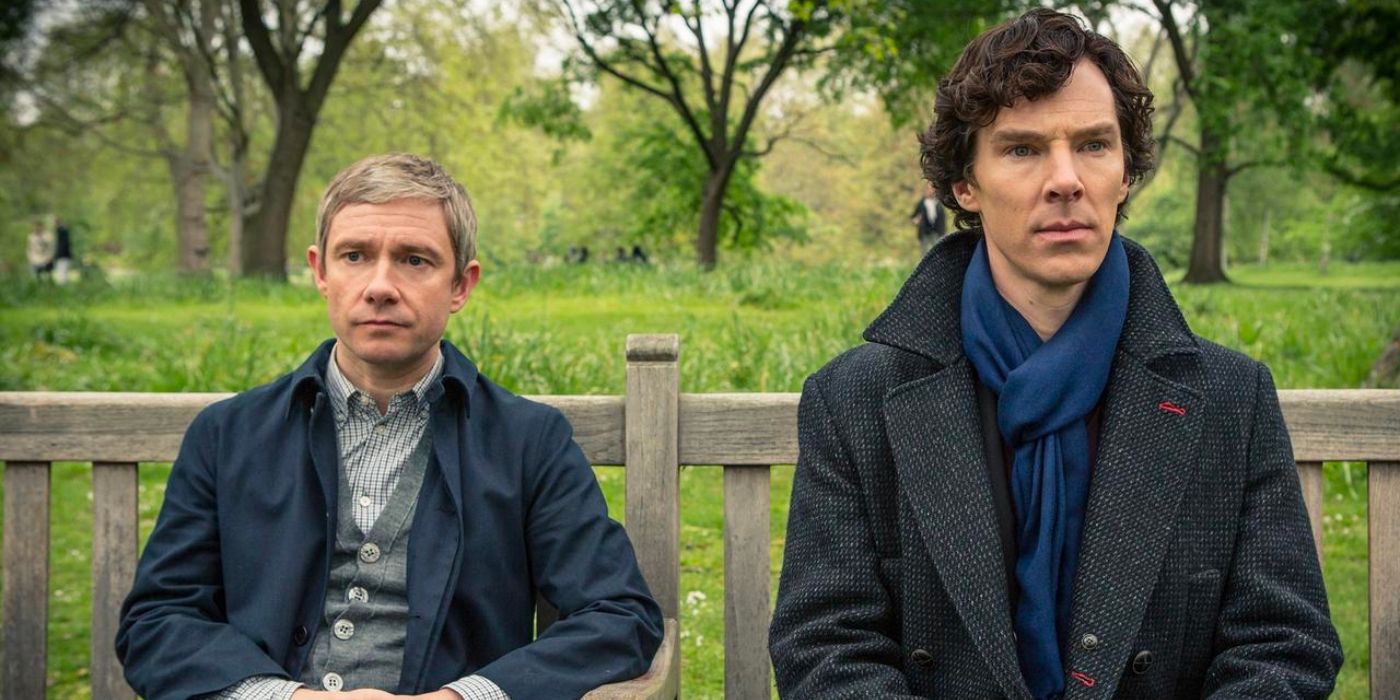 Sherlock Holme and Watson sit on a park bench and look ahead in Sherlock.