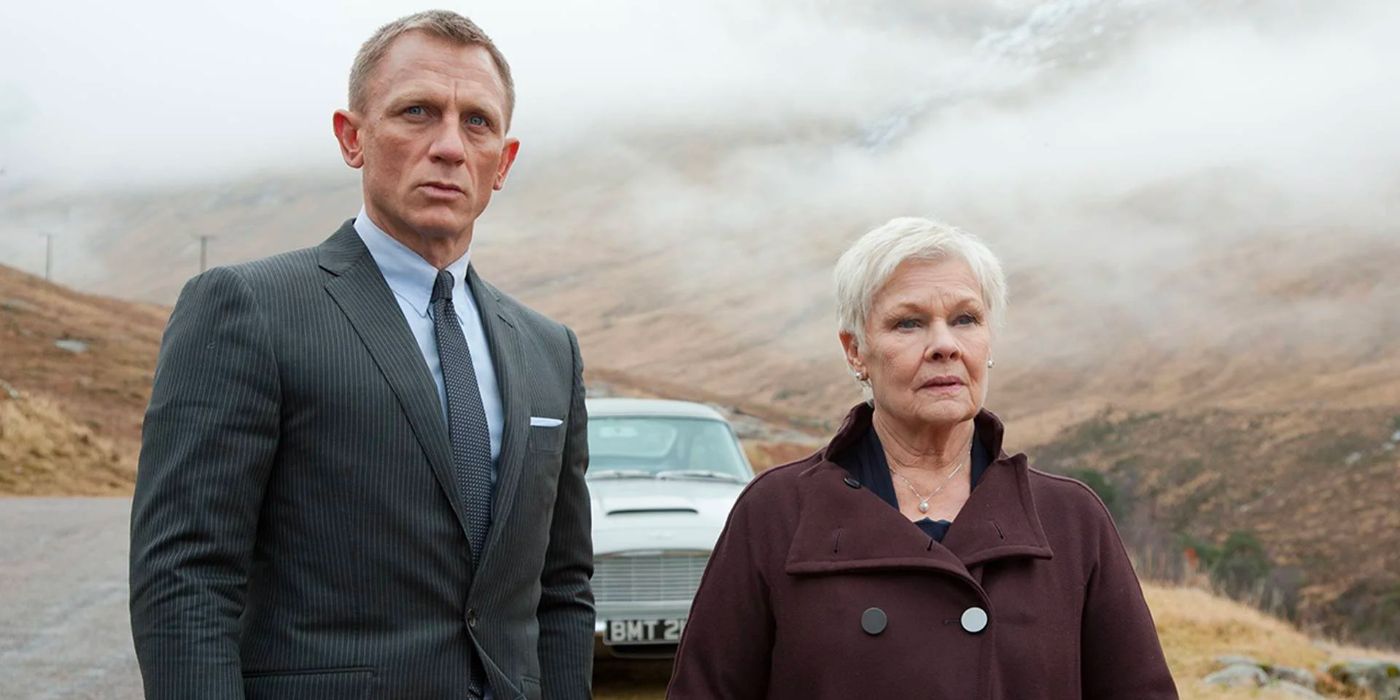 James Bond and M stand together in the misty Scottish countryside with 007's famous Aston Martin behind them.
